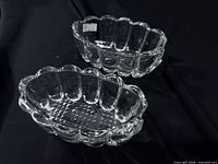 Top view of two clear pressed glass ashtrays showing scalloped edges and diamond pattern base