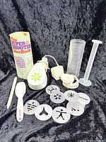 Complete set laid out: motor handle, barrel, plunger, ring, spoon, cleaning tool, idea book, ten discs