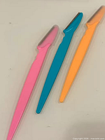 Three razors in pink, blue and orange laid out side-by-side