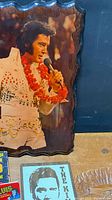 Scalloped-edge glossy photo plaque of Elvis Presley with portion of other items visible
