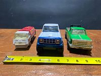 Front view of three metal toy trucks for scale