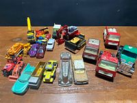 Group of vintage die-cast cars, trucks and construction toys laid out on table