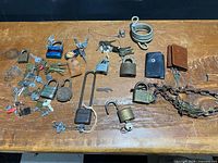Full lot overview showing padlocks, keys, chain, cable lock and key wallets on table
