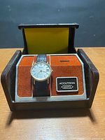 Watch in open presentation box showing dial, strap, and Accutron Quartz plaque