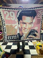 Front view of woven Elvis Presley stamp design blanket held up to show full graphic and fringe