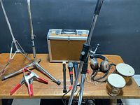 overview of lot on bench showing stands, case, microphones, bongos, headphones, clamp
