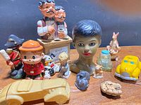 Overview of assorted ceramic figurines, cars, bust and accessories on tabletop
