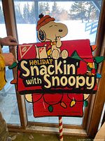 Front view of Snoopy Holiday Snackin' cardboard store display showing graphics and support pole