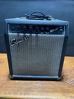 Front view of Squier BP-15 amplifier showing grille, logo, control panel and power cord