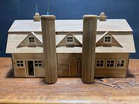 Front view of wooden model barn showing twin silos, triple-gable roof, windows, and doors