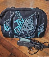 TNA duffel bag front view with straightener placed in front