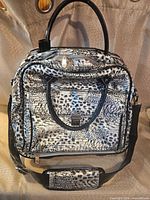 Front view of animal-print wheeled laptop bag with shoulder strap and handles