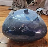 Dark glossy ceramic fire gel pot with lid and attached snuffer tool visible