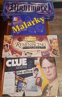 Stacked view of four board game boxes: Nightmare, Malarky, Reminiscing, Clue The Office