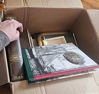 Open box showing photo albums and stack of frames