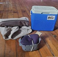 Cooler, smoker cover and skewer maker set grouped on floor