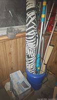 Rolled outdoor rug, blue bucket with pool poles and boxed solar heater mat