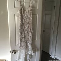 Front view of white lace evening gown hanging on door