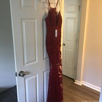 Full view of red lace evening dress hanging on door