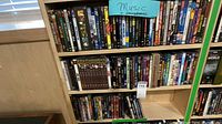 Four shelves of a bookcase holding rows of DVD cases identified as music and documentary titles