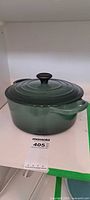 Green Le Creuset Dutch oven with lid on shelf