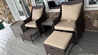 two faux wicker armchairs with cushions, two pull-out ottomans, side table, storage box on deck