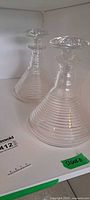 Two matching ribbed cut glass decanters with stoppers on shelf