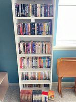 Full height view of white shelving unit filled with VHS tapes and box sets