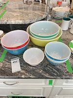 Assorted Pyrex mixing bowls and one white bowl displayed on countertop