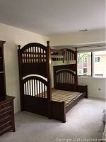 Front view of the wood bunk bed showing full bottom and single top with arched headboards and footboards, decorative posts.