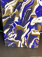 Full view of portrait-oriented abstract acrylic painting with blue, white, gold-brown, black swirls