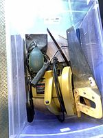 Bin containing circular saw, orbital sander, hand saws and accessories