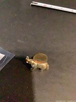 Mini brass elephant figurine with coin inserted in slot on back