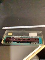 Full view of passenger coach in clear plastic box with ruler for scale