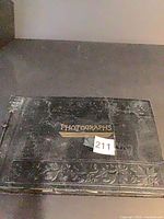 Closed black photo album front cover with gilt title