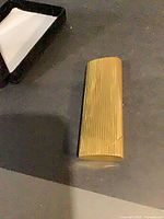 Full view of gold ribbed metal lighter lying flat