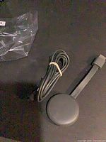 Chromecast dongle and USB power cable on black surface