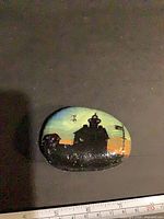 Front view of painted rock showing full lighthouse sunset artwork