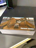 Front of sealed retail box showing cordless handheld vacuum cleaner
