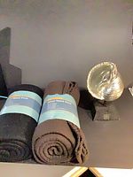 Two rolled throws and shell sculpture on shelf