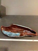 Top view of glossy brown ceramic bowl with blue accent and ruler for scale