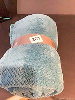 Rolled light blue polyester throw blanket with band