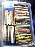 Top view of plastic bin filled with roughly 37 DVD cases showing sample spine titles
