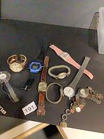 Group shot of all ten watches laid out on black surface