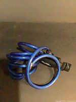 Coiled blue braided steel cable bike lock showing keyed lock head