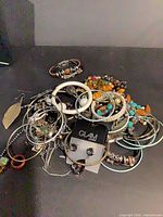Pile of assorted costume jewelry including bangles, beaded bracelets, necklaces and Glam earrings