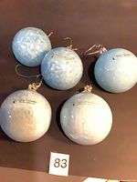 Five light-blue spherical ornaments, reverse side with brand text visible