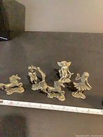 All five pewter figurines lined next to ruler for scale