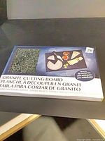 Front of boxed Rama Design granite cutting board showing size and pattern