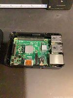 Top angle of Raspberry Pi board seated in black case, showing ports and GPIO header